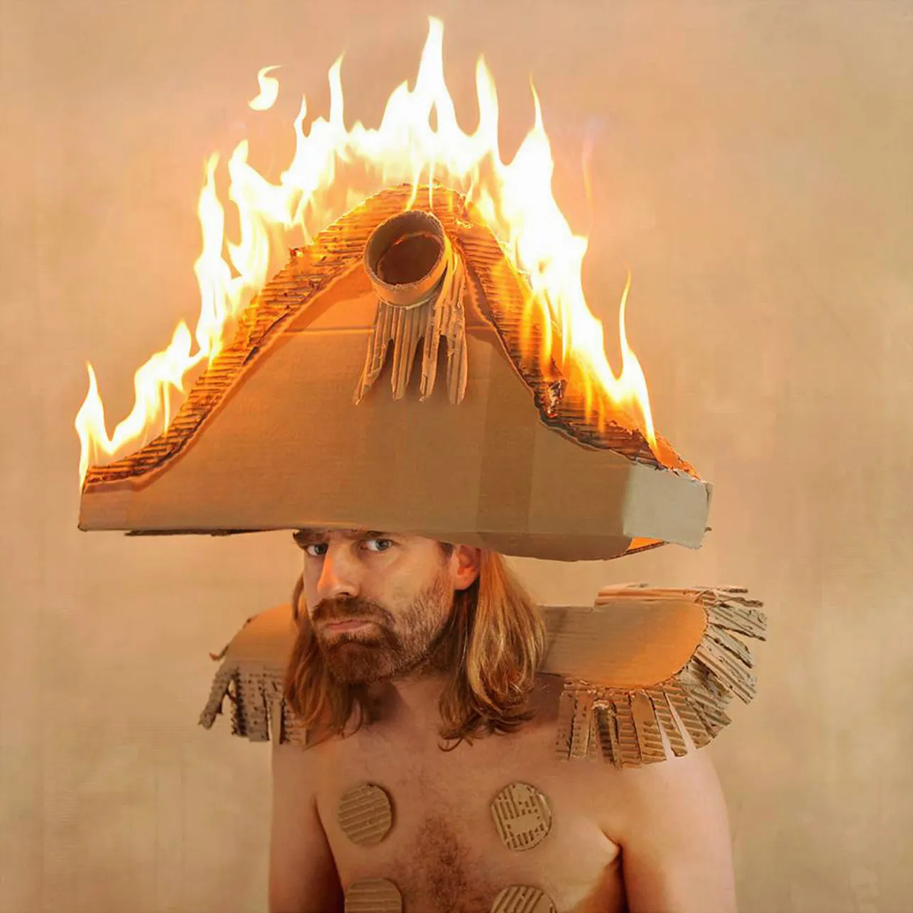 Portrait of a man wearing a burning cardboard hat and shoulder armor